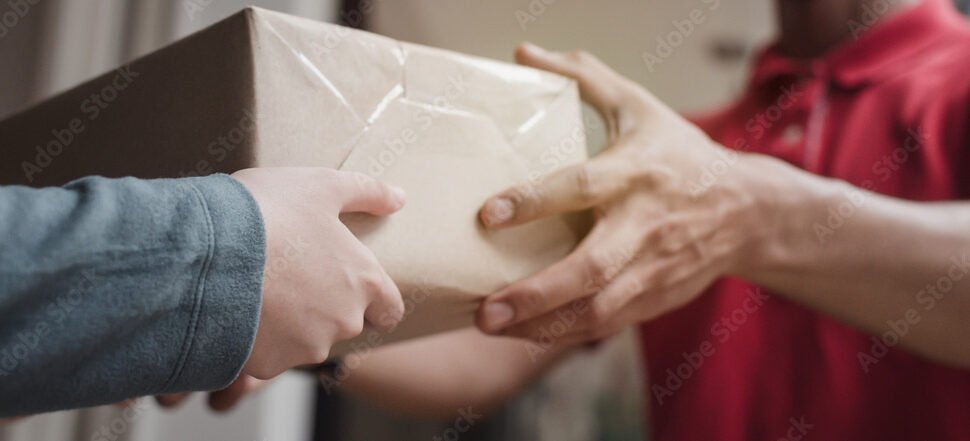 Panoramic banner. delivery service man in red uniform with woman customer receiving parcel post box from courier at home, cargo shipping, express delivery service, online shopping and logistic concept
