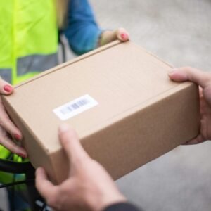 Close-up of hands exchanging a cardboard box outdoors, symbolizing delivery service in Portugal.